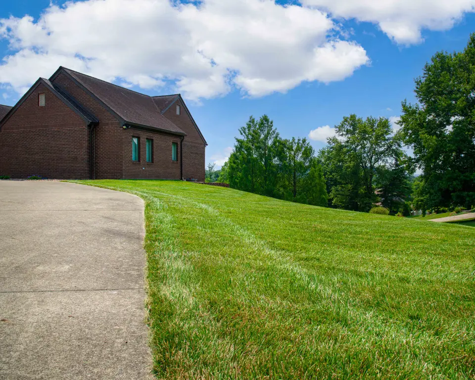 Freshly striped lawn beside a walkway in front of a brick home
